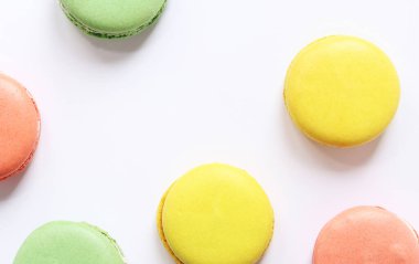 Beyaz arka planda tatlı renkli makaronlar. Lezzetli hamur işleri, düz yatak. Yemek arkaplanı. Şekerler. Beyaz arka planda parlak Fransız badem kurabiyeleri, üst manzara. Renkli badem kurabiyesi çeşitleri
