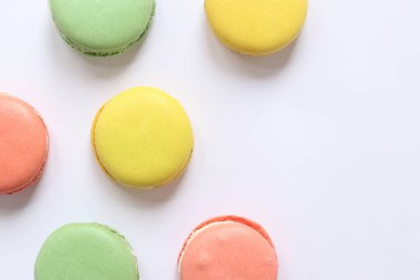 Beyaz arka planda tatlı renkli makaronlar. Lezzetli hamur işleri, düz yatak. Yemek arkaplanı. Şekerler. Beyaz arka planda parlak Fransız badem kurabiyeleri, üst manzara. Renkli badem kurabiyesi çeşitleri