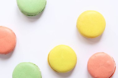 Beyaz arka planda tatlı renkli makaronlar. Lezzetli hamur işleri, düz yatak. Yemek arkaplanı. Şekerler. Beyaz arka planda parlak Fransız badem kurabiyeleri, üst manzara. Renkli badem kurabiyesi çeşitleri