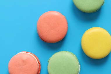 Mavi parlak arka planda makarnalar. Lezzetli hamur işleri, düz yatak. Yemek arkaplanı. Şekerler. Mavi arka planda parlak Fransız badem kurabiyeleri, üst manzara. Renkli badem kurabiyesi çeşitleri