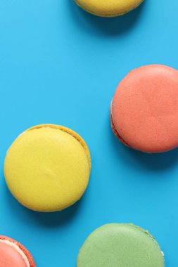 Mavi parlak arka planda makarnalar. Lezzetli hamur işleri, düz yatak. Yemek arkaplanı. Şekerler. Mavi arka planda parlak Fransız badem kurabiyeleri, üst manzara. Renkli badem kurabiyesi çeşitleri