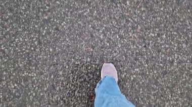 Islak asfalt üzerinde yürüyen insan ayaklarının yakın çekimi. Yağmurlu havada, ilkbaharda, sonbaharda ya da yazda yürümek. Yürüyüş. Geniş mavi kotlu ve spor ayakkabılı bir kadın sokakta yürüyor, ilk bakışta...