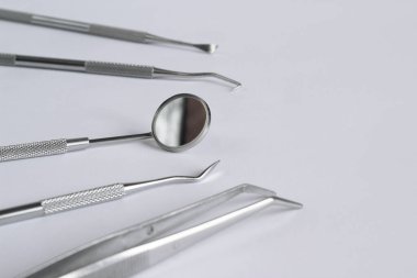 Hafif arka planda diş aletleri koleksiyonu. Diş aynası, cımbız ve diş eti hastalıklarının tedavisinde kullanılan birkaç kanca. Tanısal diş aygıtı seti