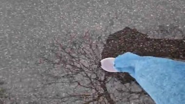 Islak asfalt üzerinde yürüyen insan ayaklarının yakın çekimi. Yağmurlu havada yürüyorum. Yürüyüş. Geniş mavi kotlu ve spor ayakkabılı kadın bacakları sokakta yürüyor, ilk bakışta. Yağmurda yürüyorum