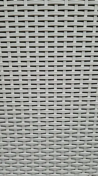 Çamaşır sepetinin dokunmuş plastik yüzeyinin yakın çekimi. Sentetik plastik desenlere yakın çekim. Plastik ev sepetlerinin dokunmuş yüzeylerinin yakın çekimi. Doku. Simetrik desenli plastik rattan