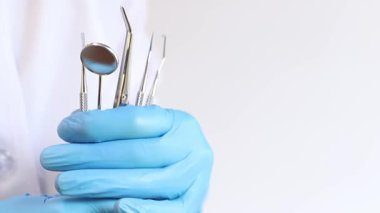 Diş aletleri bir dişçinin elinde, yakın plan. Diş aynası, diş ve diş eti hastalıklarının tedavisinde kullanılan cımbız ve kancalar. Tanısal diş aygıtı seti