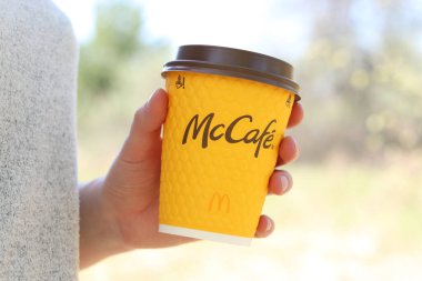 Kyiv, Ukrayna - 21 Nisan 2025: McDonalds 'dan tek kullanımlık kahve kadınların elinde. Doğada bir fincan kahveyle dolaşmak, kahve götürmek. Fast food. Latte veya cappuccino. MK Kafe