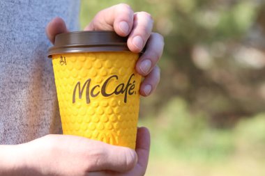 Kyiv, Ukrayna - 21 Nisan 2025: McDonalds 'dan tek kullanımlık kahve kadınların elinde. Doğada bir fincan kahveyle dolaşmak, kahve götürmek. Fast food. Latte veya cappuccino. MK Kafe