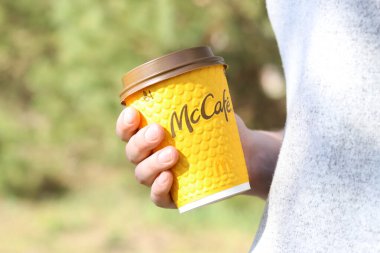 Kyiv, Ukrayna - 21 Nisan 2025: McDonalds 'dan tek kullanımlık kahve kadınların elinde. Doğada bir fincan kahveyle dolaşmak, kahve götürmek. Fast food. Latte veya cappuccino. MK Kafe