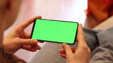 Yeşil ekran. Telefonla kadın ellerine yakın çekim. Yeşil ekranlı telefon. Kanepede oturan yeşil ekranlı akıllı telefonlu bir kız. Modelleme. Modern aletler. Yaratıcı kavram için alan