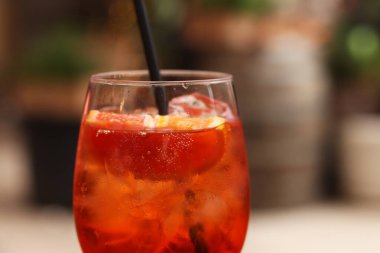Aperol Spritz. Soğuk, ferahlatıcı alkollü kokteyl Aperol Spritz. Bulanık bir arka planda kokteyl yakın plan. Kamışlı bir bardakta alkollü içki. Geleneksel İtalyan alkollü içecek