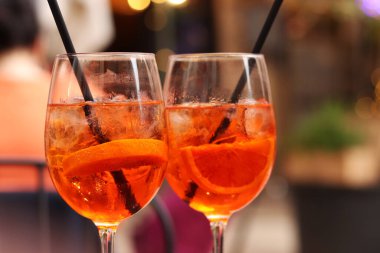 Aperol Spritz. Soğuk, ferahlatıcı alkollü kokteyl Aperol Spritz. Bulanık bir arka planda kokteyl yakın plan. Kamışlı bir bardakta alkollü içki. Geleneksel İtalyan alkollü içecek