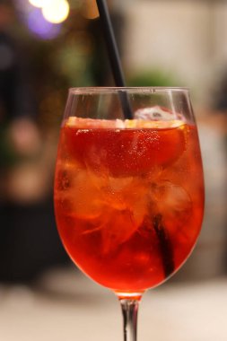 Aperol Spritz. Soğuk, ferahlatıcı alkollü kokteyl Aperol Spritz. Bulanık bir arka planda kokteyl yakın plan. Kamışlı bir bardakta alkollü içki. Geleneksel İtalyan alkollü içecek