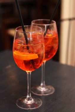 Aperol Spritz. Soğuk, ferahlatıcı alkollü kokteyl Aperol Spritz. Bulanık bir arka planda kokteyl yakın plan. Kamışlı bir bardakta alkollü içki. Geleneksel İtalyan alkollü içecek