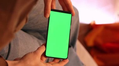 Yeşil ekran. Telefonla kadın ellerine yakın çekim. Yeşil ekranlı telefon. Kanepede oturan yeşil ekranlı akıllı telefonlu bir kız. Modelleme. Modern aletler. Yaratıcı kavram için alan