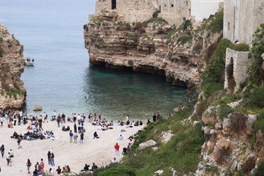 Polignano a Mare, İtalya - 13 Nisan 2025: Lama Monachile Körfezi manzarası. Apulia. Seyahat fotoğrafçılığı. Güzel manzara. Adriyatik Denizi 'nin deniz manzarası. Kumsal. Kaya kıyısı ve turkuaz su