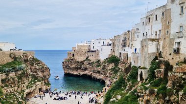 Polignano a Mare, İtalya - 13 Nisan 2025: Lama Monachile Körfezi manzarası. Apulia. Seyahat fotoğrafçılığı. Güzel manzara. Adriyatik Denizi 'nin deniz manzarası. Kumsal. Kaya kıyısı ve turkuaz su