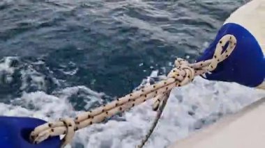 Teknenin yan tarafına bağlı bir tekne tamponu. Deniz çamurluğu ya da tekne tamponu. Deniz gezisi. Suç ortağı. Denizde hızlı tekne gezisi, deniz spreyi. Deniz çamurlukları. Bir tekne ya da yelkenli için plastik çamurluk