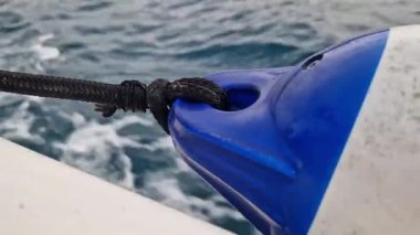 Teknenin yan tarafına bağlı bir tekne tamponu. Deniz çamurluğu ya da tekne tamponu. Deniz gezisi. Suç ortağı. Denizde hızlı tekne gezisi, deniz spreyi. Deniz çamurlukları. Bir tekne ya da yelkenli için plastik çamurluk