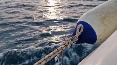 Teknenin yan tarafına bağlı bir tekne tamponu. Deniz çamurluğu ya da tekne tamponu. Deniz gezisi. Suç ortağı. Denizde hızlı tekne gezisi, deniz spreyi. Deniz çamurlukları. Bir tekne ya da yelkenli için plastik çamurluk