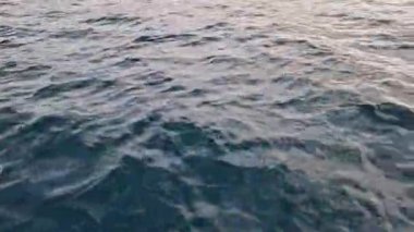 Tekneden deniz dalgalarının görüntüsü. Deniz. Deniz yürüyüşü. Dalgalarda yüzmek. Tekneden denizin yan yüzeyi. Su sıçrıyor. Seyahat videosu