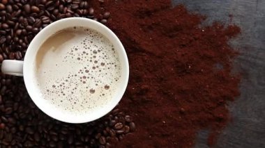 Cappuccino, en iyi manzara. Kahve çekirdekleri ve öğütülmüş kahvenin arasında bir fincan kapuçino. Kavrulmuş kahve çekirdekleri arasında bir fincan aromatik kahve. Canlandırıcı bir içki. Boşluğu kopyala