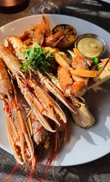 Tabakta, restoranda pişmiş deniz mahsulleri. Soslu ve limonlu kabuklular. Lezzetli ve sağlıklı yiyecekler. Deniz ürünleri tabağının çok güzel bir sunumu. Büyük karidesler, langoustine