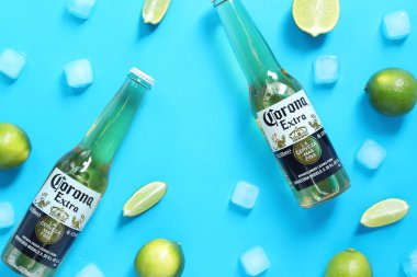 Kyiv, Ukrayna - 10 Mayıs 2025: Mavi arka planda limon ve buz küplü ekstra Corona biraları. Corona hafif bir bira. Limonlu bira, üst manzara, boş yer. Soğuk içecekler.