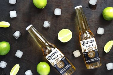 Kyiv, Ukrayna - 10 Mayıs 2025: Ahşap zemin üzerinde limon ve buz küpleri olan ekstra Corona biraları. Corona hafif bir bira. Limonlu bira, üst manzara, boş yer. Koyu bir masada bira.