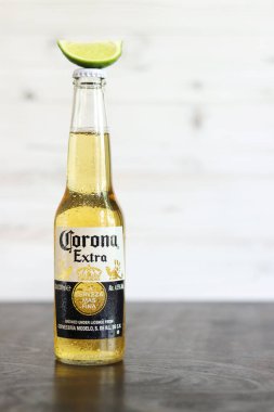 Kyiv, Ukrayna - 10 Mayıs 2025: Corona Ekstra bira şişesi üzerinde limon dilimi, ahşap arka planda bira duruyor. Corona hafif bir bira. Limonlu bira, yan görüş, boş yer. Soğuk içecek.