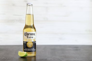 Kyiv, Ukrayna - 10 Mayıs 2025: Corona Ekstra limonlu bira, ahşap arka planda bira duruyor. Corona hafif bir bira. Limonlu şişe bira, yan görüş, boş yer. Soğuk içecek.