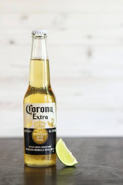Kyiv, Ukrayna - 10 Mayıs 2025: Corona Ekstra limonlu bira, ahşap arka planda bira duruyor. Corona hafif bir bira. Limonlu şişe bira, yan görüş, boş yer. Soğuk içecek.