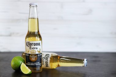 Kyiv, Ukrayna - 10 Mayıs 2025: Corona Ekstra limonlu bira, ahşap arka planda bira duruyor. Corona hafif bir bira. Limonlu şişe bira, yan görüş, boş yer. Soğuk içecek.