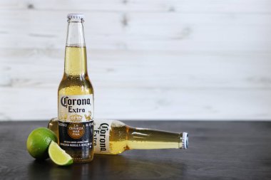 Kyiv, Ukrayna - 10 Mayıs 2025: Corona Ekstra limonlu bira, ahşap arka planda bira duruyor. Corona hafif bir bira. Limonlu şişe bira, yan görüş, boş yer. Soğuk içecek.