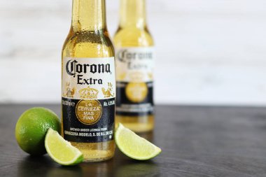 Kyiv, Ukrayna - 10 Mayıs 2025: Corona Ekstra limonlu bira, ahşap arka planda bira duruyor. Corona hafif bir bira. Limonlu şişe bira, yan görüş, boş yer. Soğuk içecek.