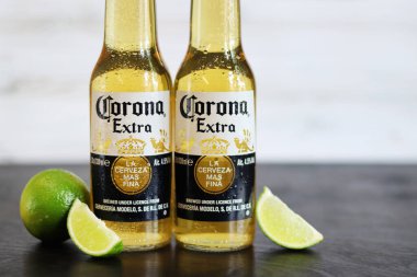 Kyiv, Ukrayna - 10 Mayıs 2025: Corona Ekstra limonlu bira, ahşap arka planda bira duruyor. Corona hafif bir bira. Limonlu şişe bira, yan görüş, boş yer. Soğuk içecek.