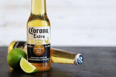 Kyiv, Ukrayna - 10 Mayıs 2025: Corona Ekstra limonlu bira, ahşap arka planda bira duruyor. Corona hafif bir bira. Limonlu şişe bira, yan görüş, boş yer. Soğuk içecek.