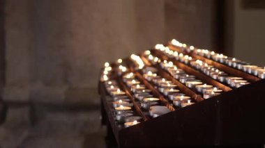 Bir manastırda, tapınakta ya da kilisede yanan mumlar. İçinde çok sayıda mum bulunan bir tezgah. Kilisede mum yakan bir şamdan. Din. Gizemciliğin atmosferi