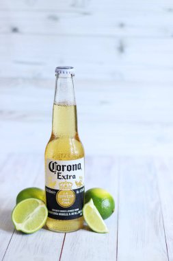 Kyiv, Ukrayna - 10 Mayıs 2025: Corona Ekstra limonlu bira, ahşap arka planda bira duruyor. Corona hafif bir bira. Limonlu şişe bira, yan görüş, boş yer. Soğuk içecek.