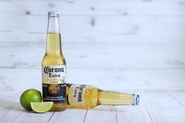 Kyiv, Ukrayna - 10 Mayıs 2025: Corona Ekstra limonlu bira, ahşap arka planda bira duruyor. Corona hafif bir bira. Limonlu şişe bira, yan görüş, boş yer. Soğuk içecek.
