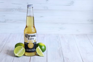 Kyiv, Ukrayna - 10 Mayıs 2025: Corona Ekstra limonlu bira, ahşap arka planda bira duruyor. Corona hafif bir bira. Limonlu şişe bira, yan görüş, boş yer. Soğuk içecek.