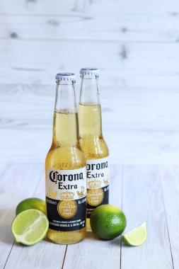 Kyiv, Ukrayna - 10 Mayıs 2025: Corona Ekstra limonlu bira, ahşap arka planda bira duruyor. Corona hafif bir bira. Limonlu şişe bira, yan görüş, boş yer. Soğuk içecek.