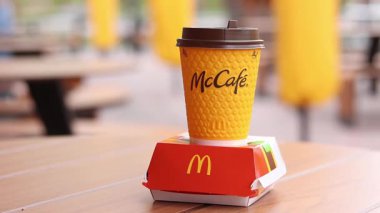 Kyiv, Ukrayna, 12 Mayıs 2025 McDonald 's Latte ve Royal Cheeseburger. Tek kullanımlık bir fincanda hazır kahve. Verandada fast food. Sarı McCafe bardağı karton bir kutunun yanında çizburgerli