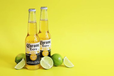 Kyiv, Ukrayna - 10 Mayıs 2025: Sarı arka planda Corona Ekstra birası. Corona hafif bir bira. Limonlu şişe bira, yan görüş, boş yer. Parlak bir arka planda alkollü içki