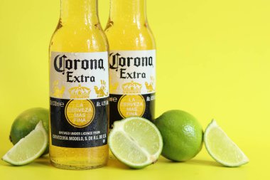 Kyiv, Ukrayna - 10 Mayıs 2025: Sarı arka planda Corona Ekstra birası. Corona hafif bir bira. Limonlu şişe bira, yan görüş, boş yer. Parlak bir arka planda alkollü içki