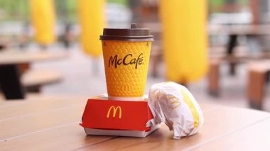 Kyiv, Ukrayna - 12 Mayıs 2025: McDonald 's Latte, Royal Cheeseburger ve Double Cheeseburger verandada. Sarı McCafe bardağı diğer fast food bardaklarının yanında. Çizburger ve kahve.