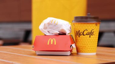 Kyiv, Ukrayna - 12 Mayıs 2025: McDonald 's Latte, Royal Cheeseburger ve Double Cheeseburger verandada. Sarı McCafe bardağı diğer fast food bardaklarının yanında. Çizburger ve kahve.