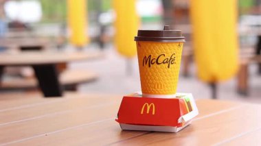 Kyiv, Ukrayna - 12 Mayıs 2025: McDonald 's Latte and Royal Cheeseburger. Tek kullanımlık bir fincanda hazır kahve. Verandada fast food. Sarı McCafe bardağı karton bir kutunun yanında çizburgerli
