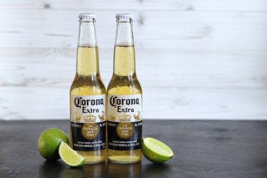 Kyiv, Ukrayna - 10 Mayıs 2025: Corona Ekstra limonlu bira, açık ahşap arka planda bira. Corona hafif bir bira. Limonlu şişe bira, yan görüş, boş yer. Tazeleyici içecek.