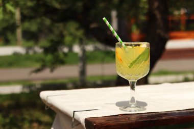 Sıcak bir yaz gününde bahçe masasında iç. Dışarıdaki ahşap bir masada kokteylli cam. Bulanık doğanın arka planına karşı bir masada limonata. Bardakta limonata ya da başka bir içecek.